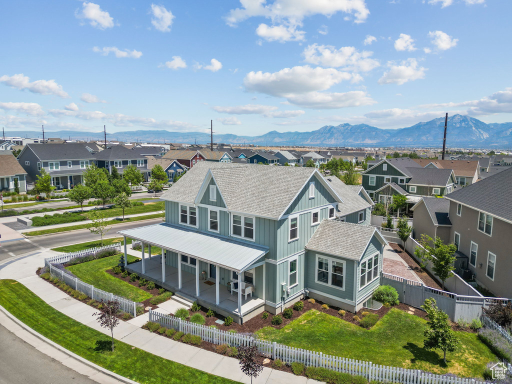 View of front of house featuring a residential view, covered porch, a shingled roof, a mountain view, and a fenced front yard