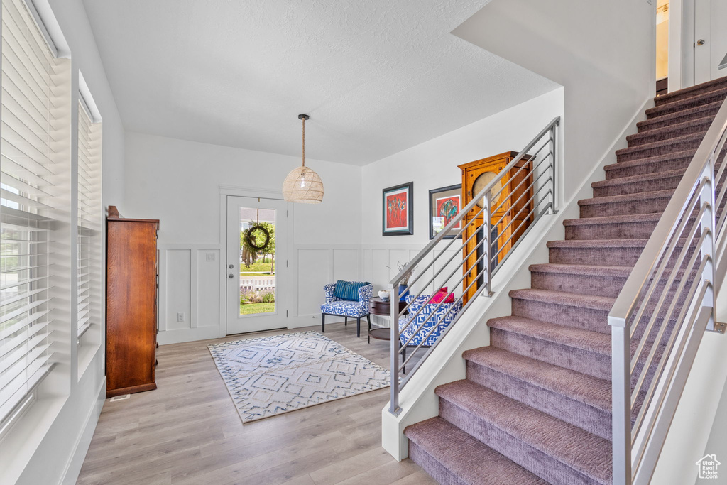 Entrance foyer featuring stairway, light wood finished floors, a wainscoted wall, and a decorative wall