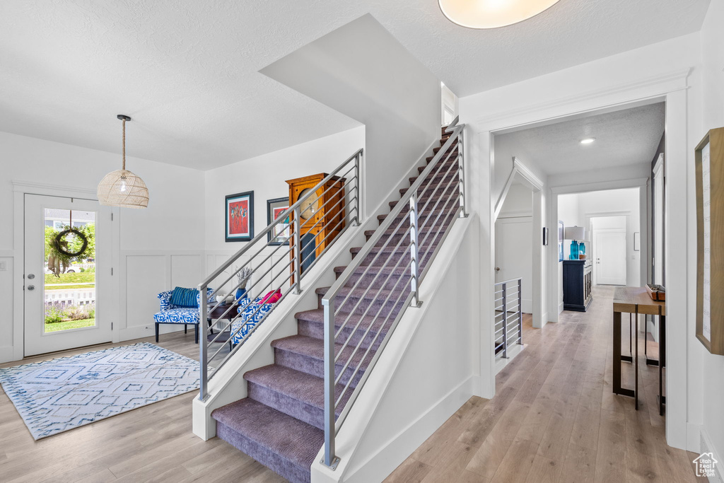 Entrance foyer featuring stairway, light wood-type flooring, and a textured ceiling