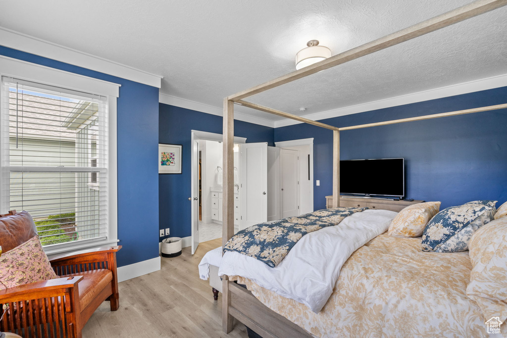 Bedroom with crown molding, wood finished floors, and a closet