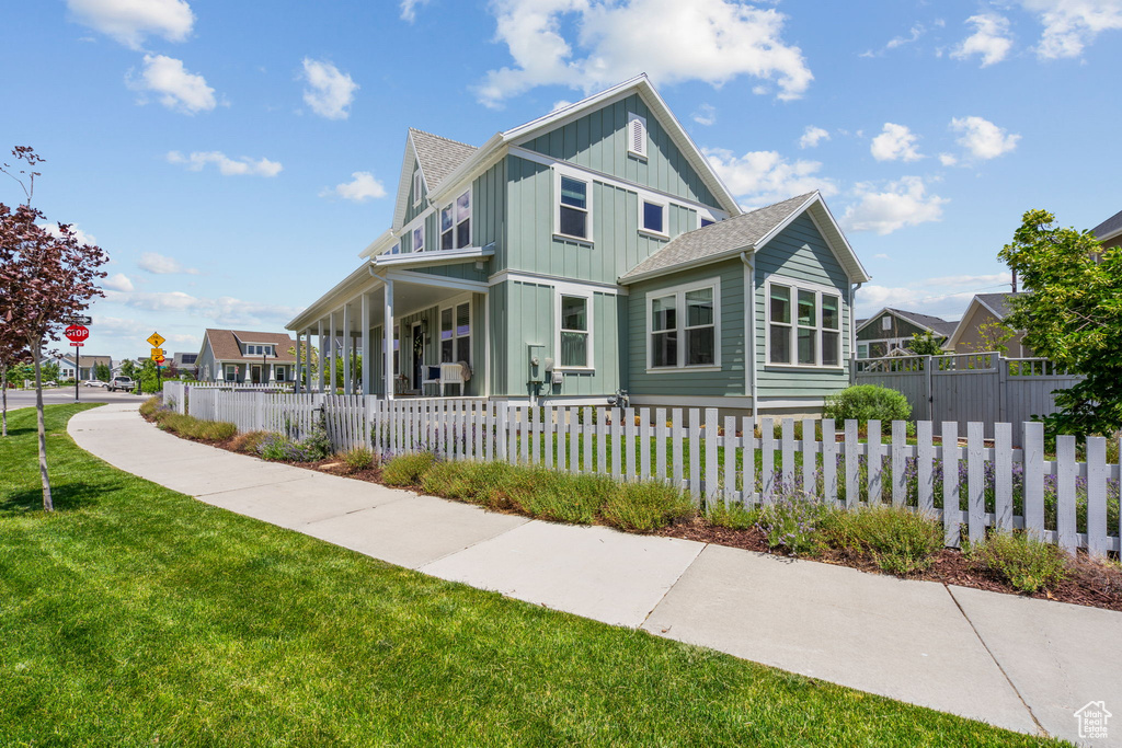 View of front facade featuring board and batten siding, a fenced front yard, covered porch, and a shingled roof