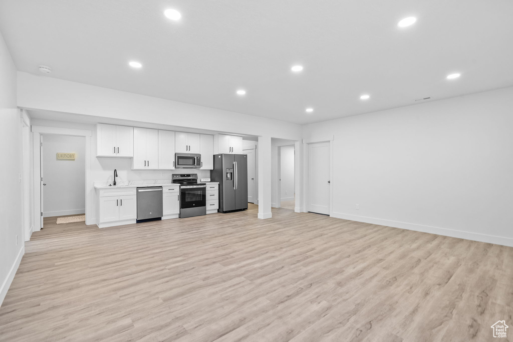 Kitchen with stainless steel appliances, white cabinetry, recessed lighting, light wood-style flooring, and light countertops