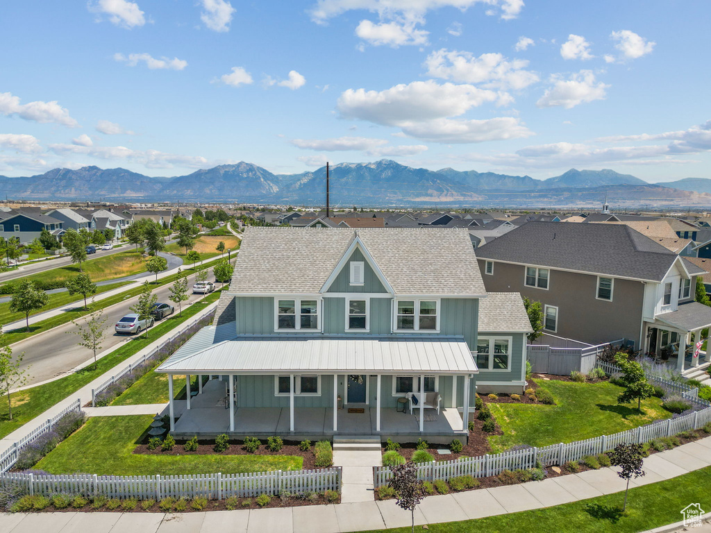 View of front of house with board and batten siding, covered porch, roof with shingles, a residential view, and a mountain view