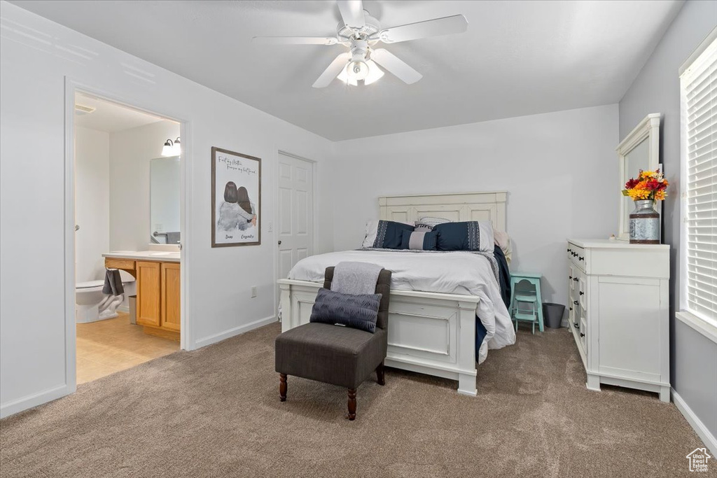 Bedroom featuring light carpet, ceiling fan, ensuite bathroom, and multiple windows