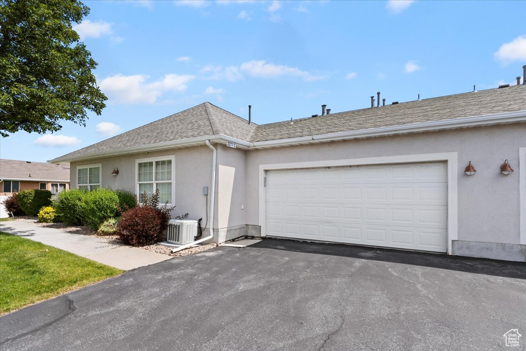 Ranch-style home featuring stucco siding, driveway, a garage, and roof with shingles