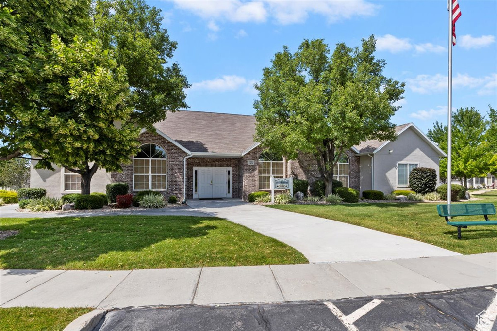 Obstructed view of property featuring a front lawn, brick siding, and driveway