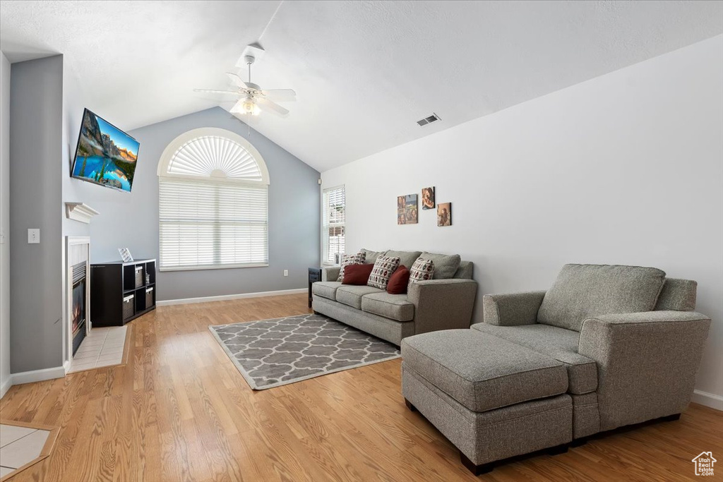 Living area featuring a ceiling fan, lofted ceiling, and light wood-style floors