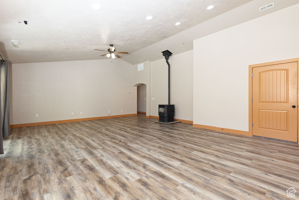 Unfurnished living room with a ceiling fan, vaulted ceiling, arched walkways, recessed lighting, and light wood-style floors