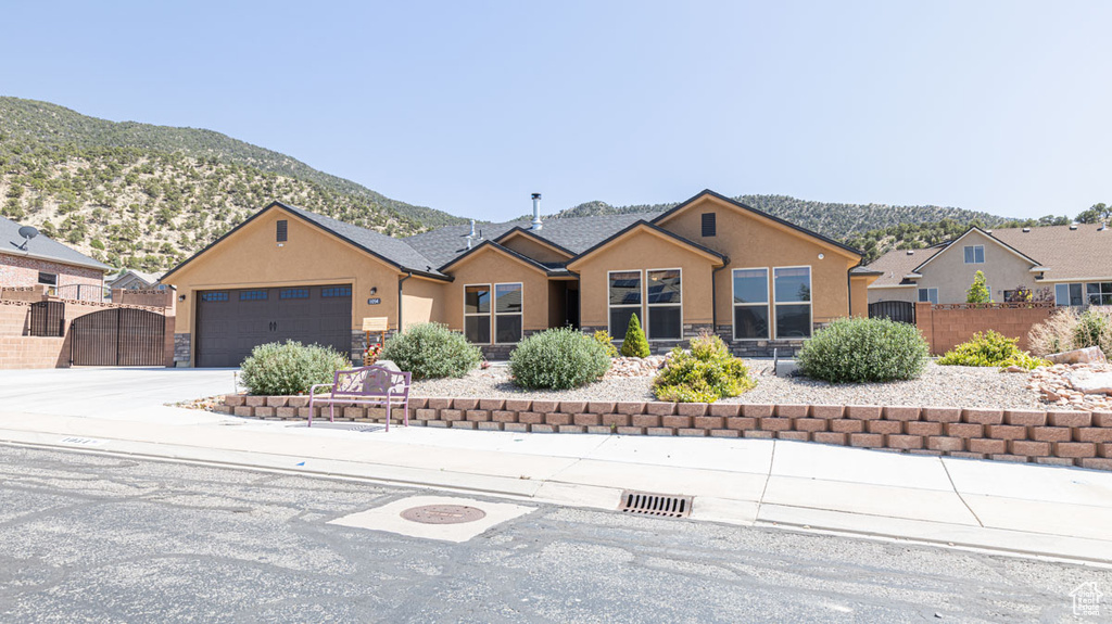 Single story home featuring stone siding, stucco siding, a mountain view, and a garage