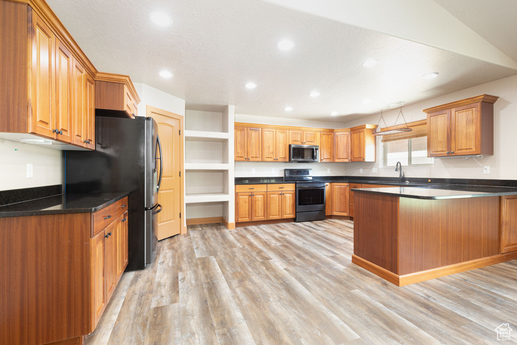 Kitchen with stainless steel electric stove, a peninsula, recessed lighting, light wood finished floors, and freestanding refrigerator