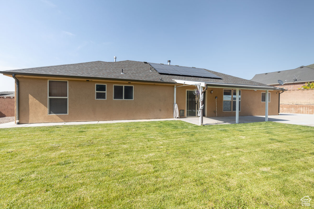 Rear view of property featuring a patio area, roof mounted solar panels, stucco siding, and a fenced backyard