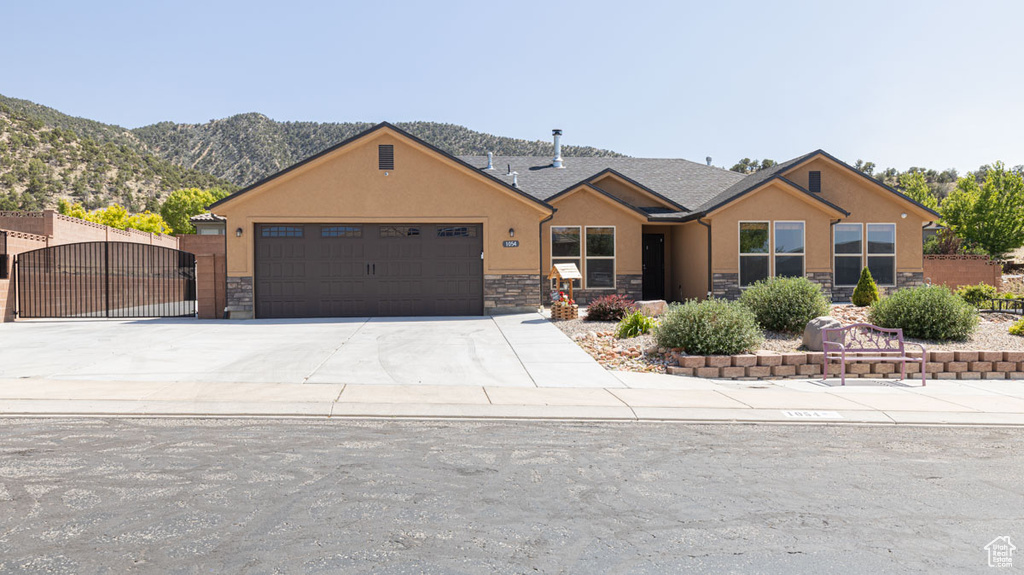 View of front of property with stone siding, an attached garage, and stucco siding
