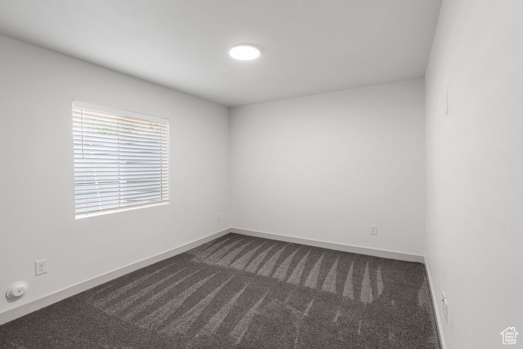Spare room with dark colored carpet and baseboards