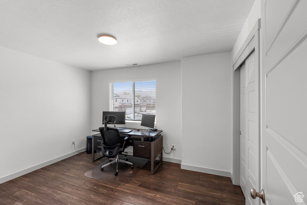 Office area featuring dark wood-style flooring and baseboards