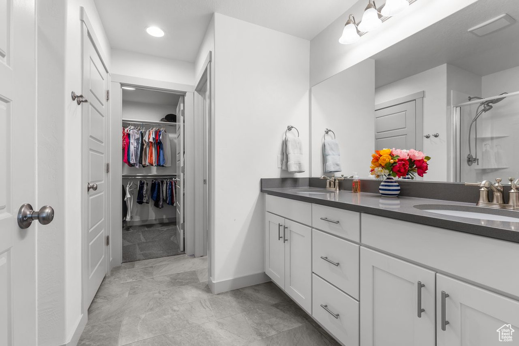 Full bathroom featuring double vanity, a shower stall, a walk in closet, and recessed lighting