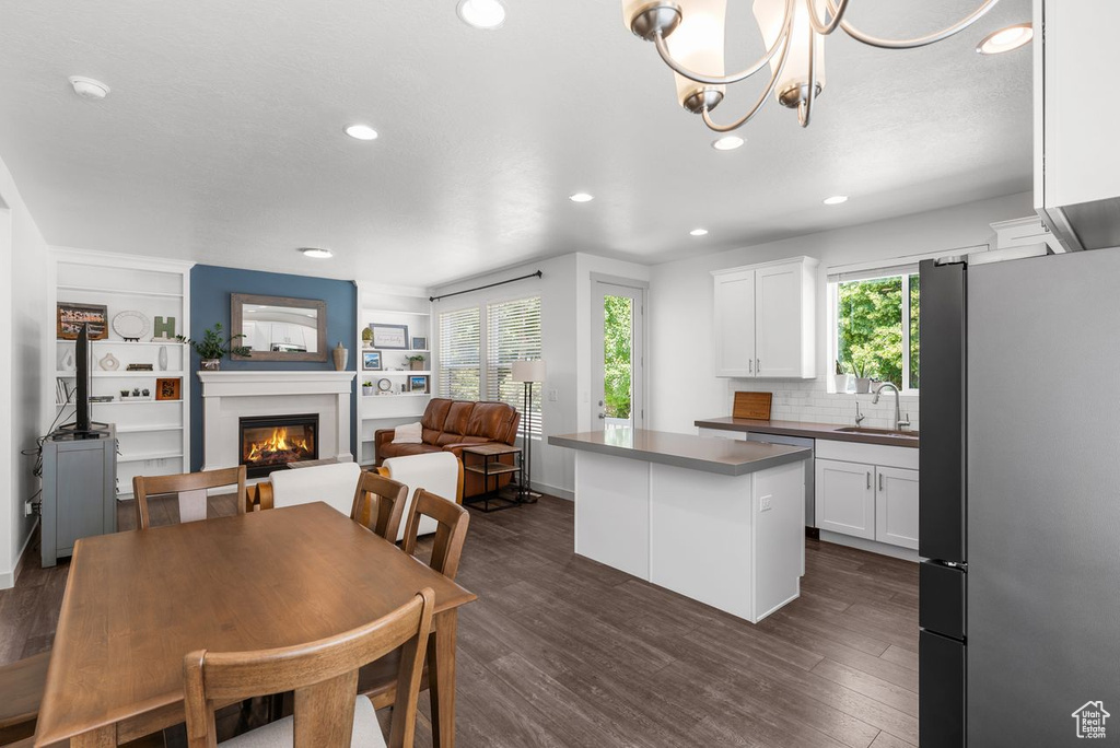 Dining room with a glass covered fireplace, recessed lighting, dark wood finished floors, a chandelier, and built in shelves