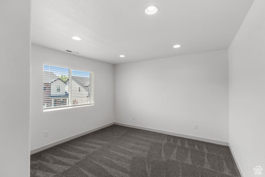 Spare room featuring dark carpet and recessed lighting