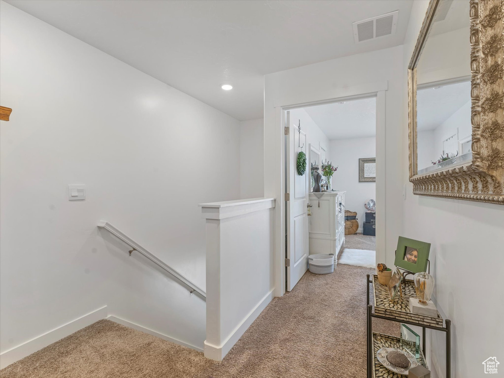 Hallway with an upstairs landing, carpet flooring, and recessed lighting