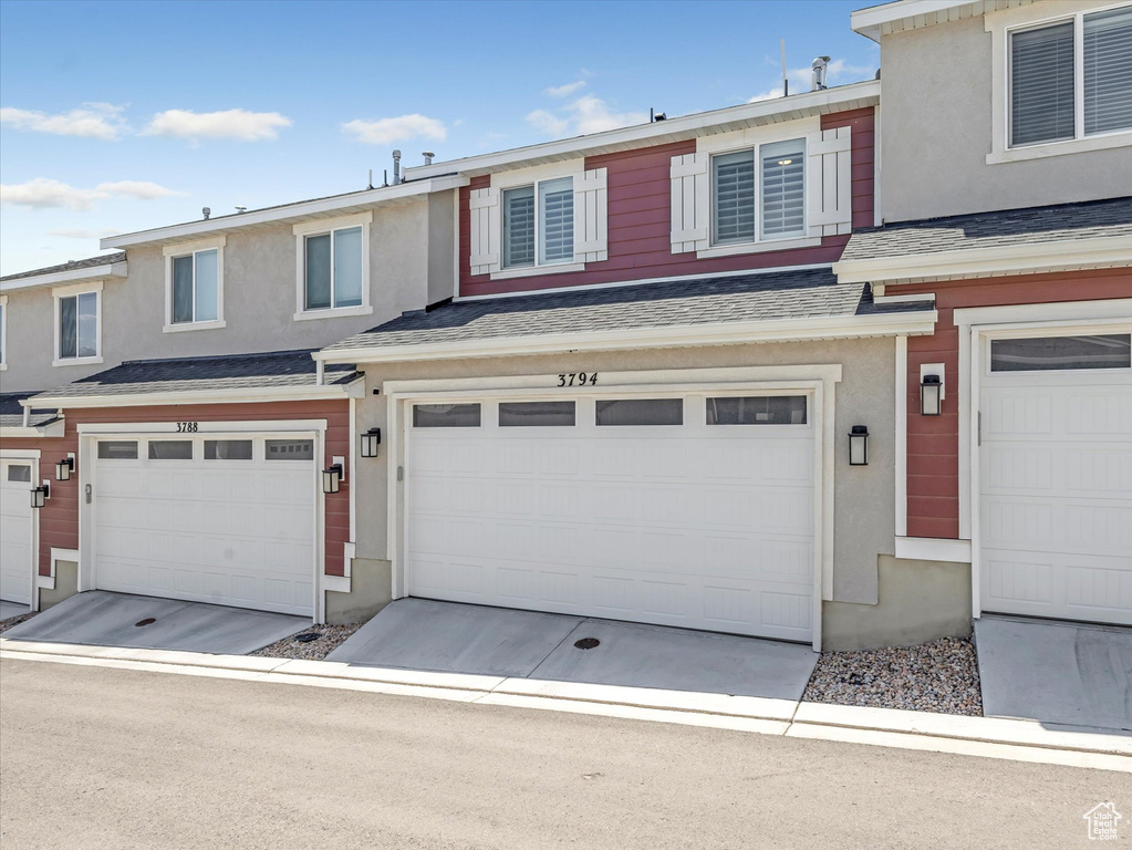 Multi unit property featuring an attached garage, stucco siding, and a shingled roof