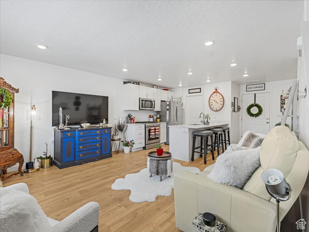 Living area featuring light wood finished floors and recessed lighting