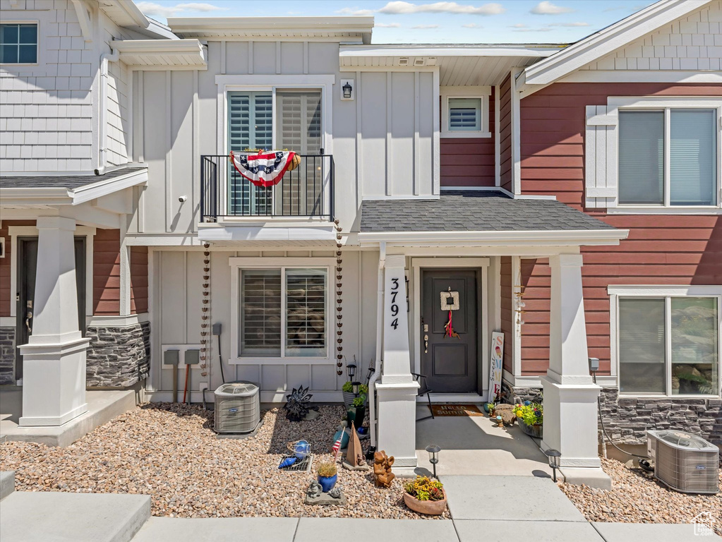View of front facade with board and batten siding, a balcony, and stone siding