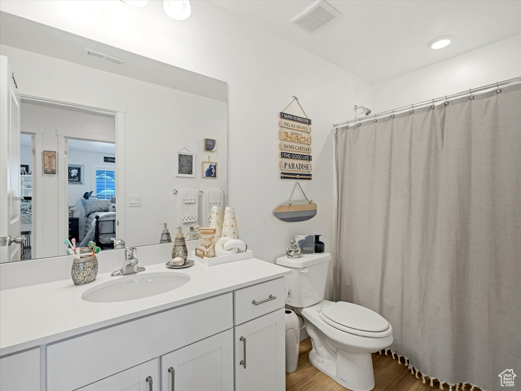 Ensuite bathroom with vanity, wood finished floors, and curtained shower