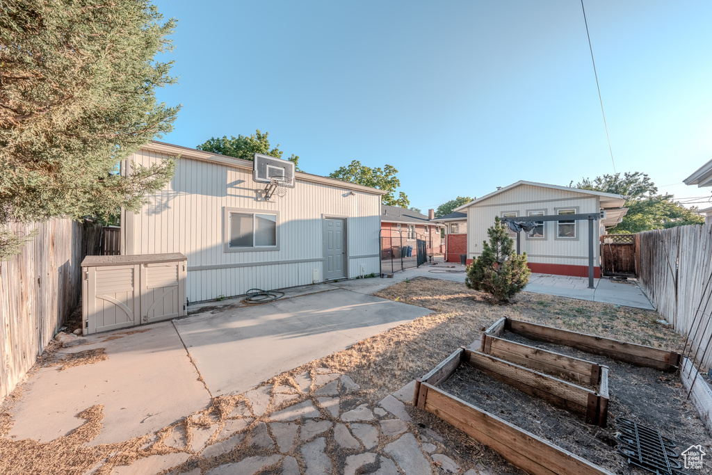 Rear view of house featuring an outbuilding, a vegetable garden, a fenced backyard, and a patio