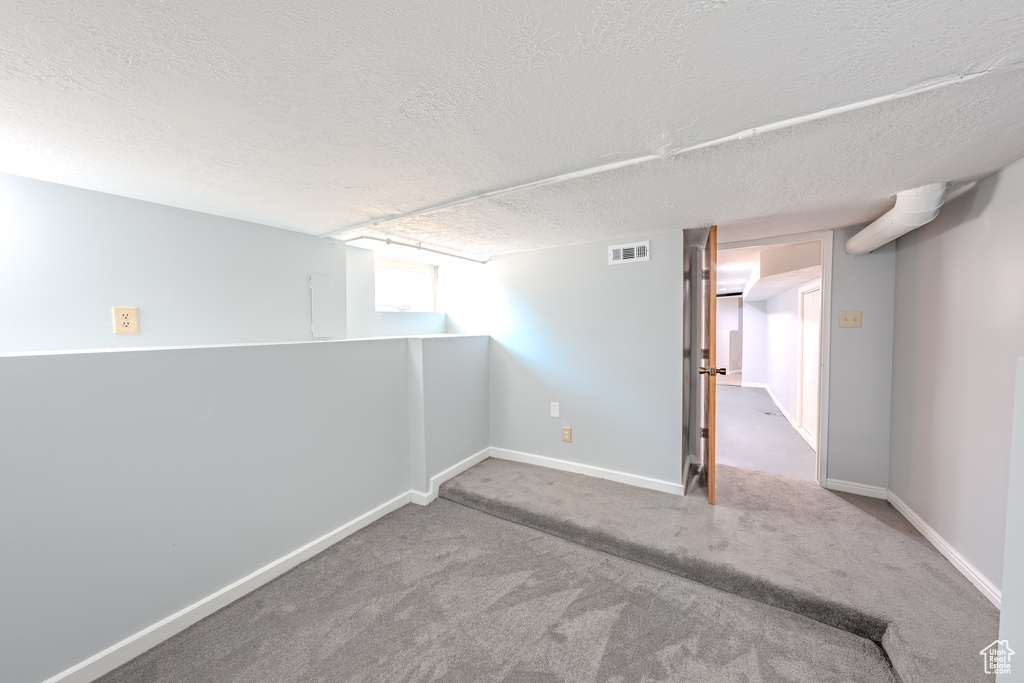 Unfurnished room featuring a textured ceiling and carpet