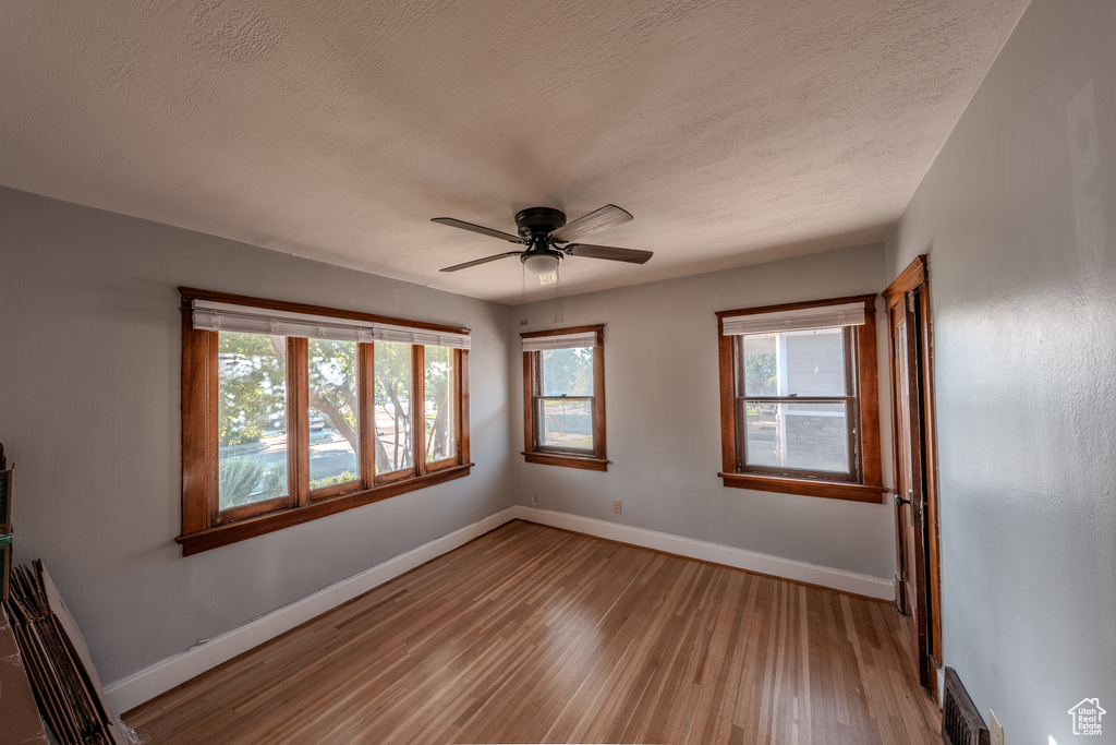 Unfurnished room with light wood-style floors, a ceiling fan, and a textured ceiling
