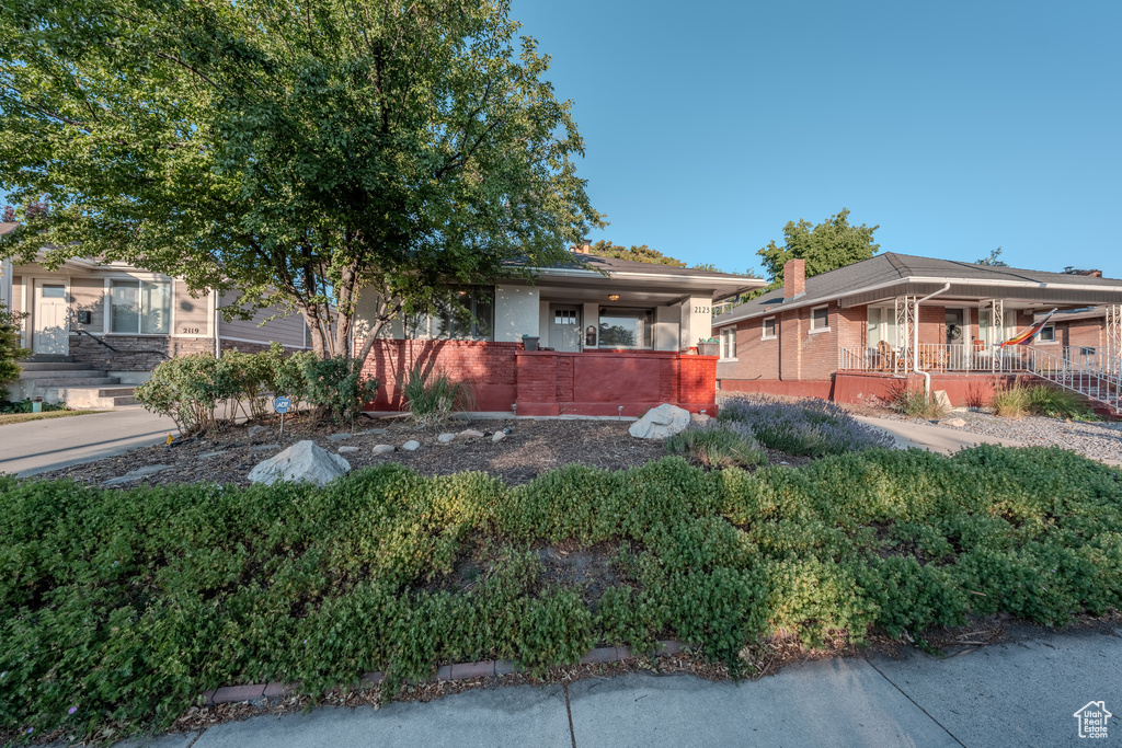 View of property hidden behind natural elements featuring a porch and brick siding