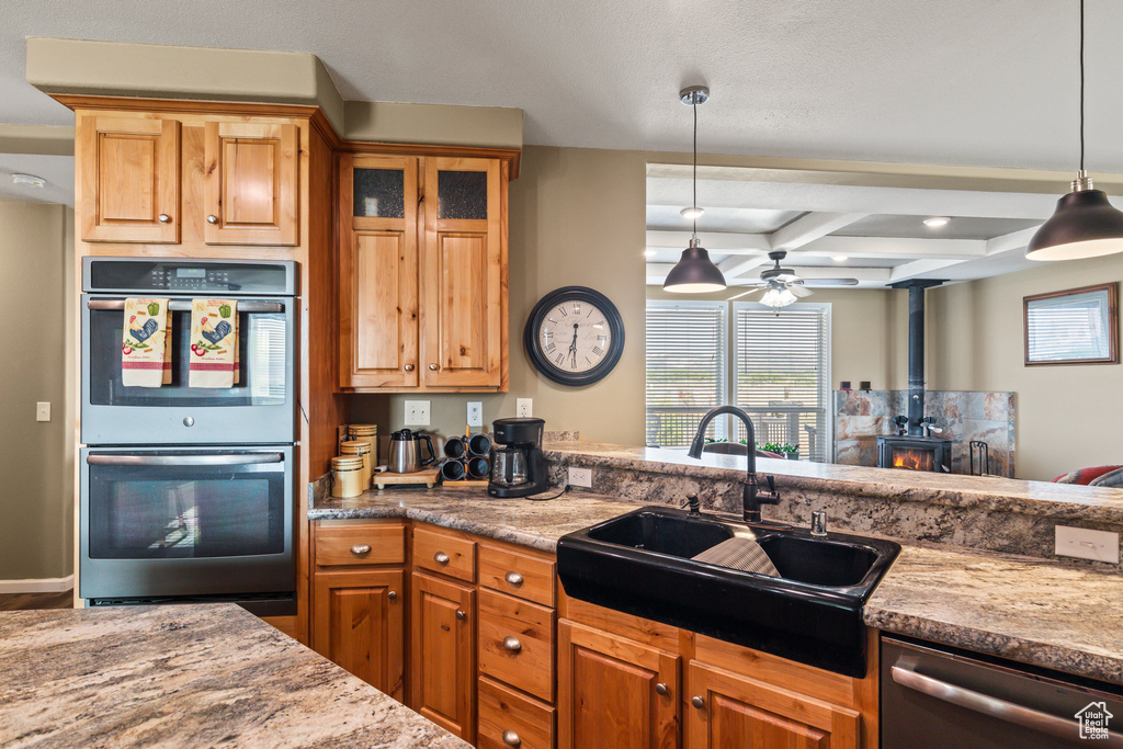 Kitchen with stainless steel appliances, a wood stove, ceiling fan, plenty of natural light, and beam ceiling