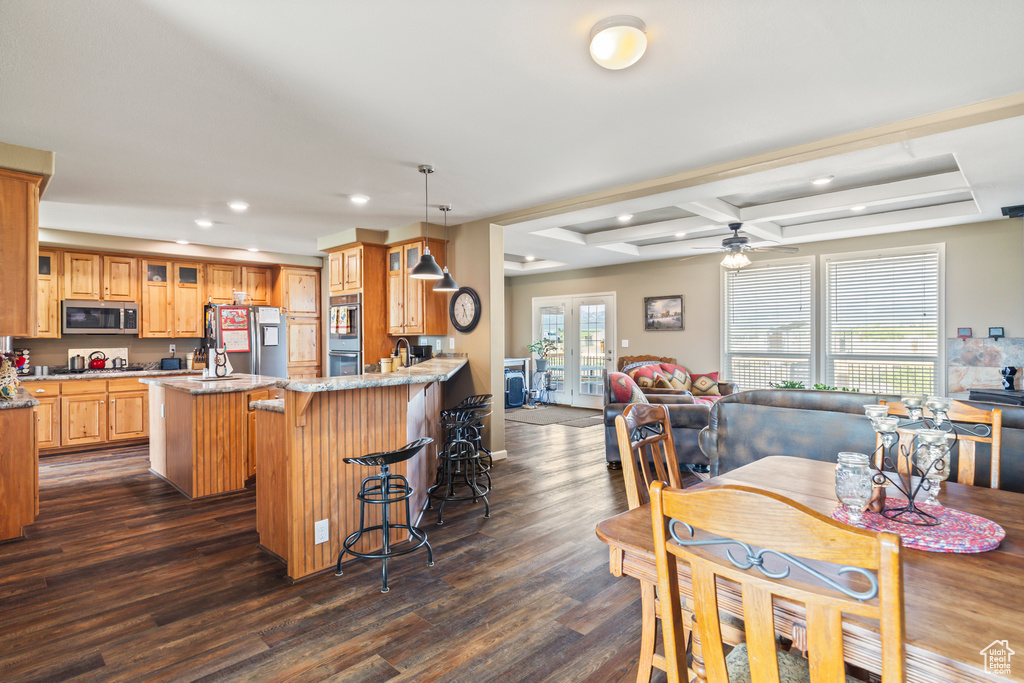 Kitchen with appliances with stainless steel finishes, dark wood finished floors, recessed lighting, glass insert cabinets, and a kitchen island