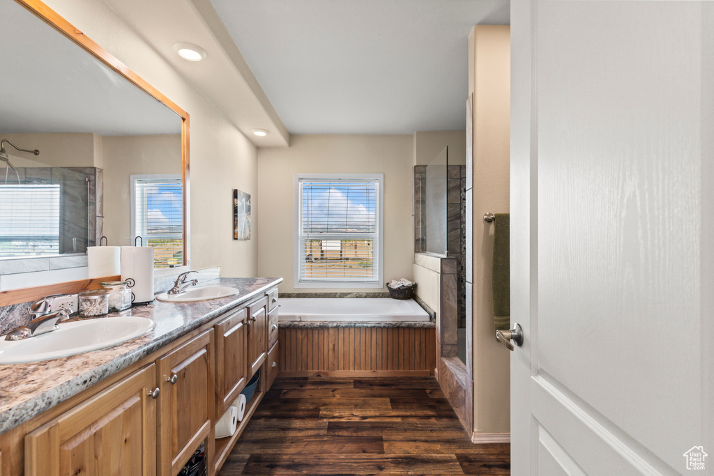 Bathroom featuring a stall shower, a bath, double vanity, and plenty of natural light
