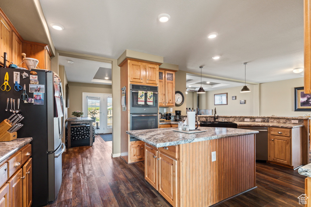 Kitchen featuring stainless steel appliances, a kitchen island, dark wood-style floors, light stone countertops, and recessed lighting