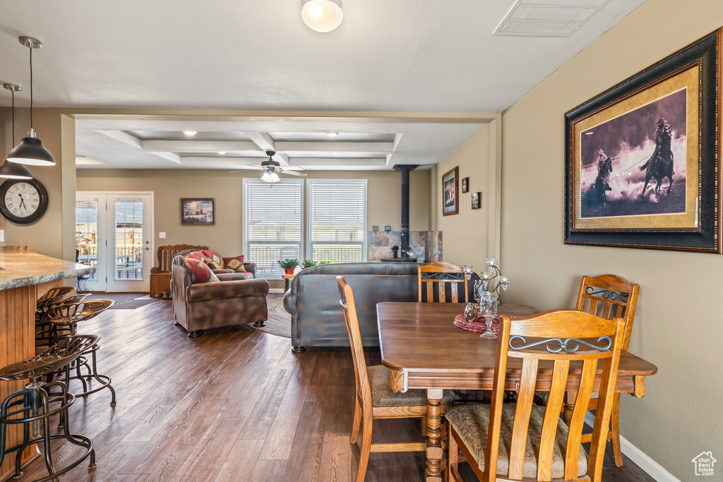 Dining space featuring plenty of natural light, dark wood-style flooring, a ceiling fan, and a wood stove