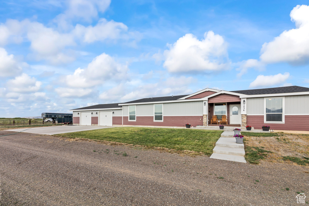 View of front of home with concrete driveway, a garage, a front lawn, and roof with shingles