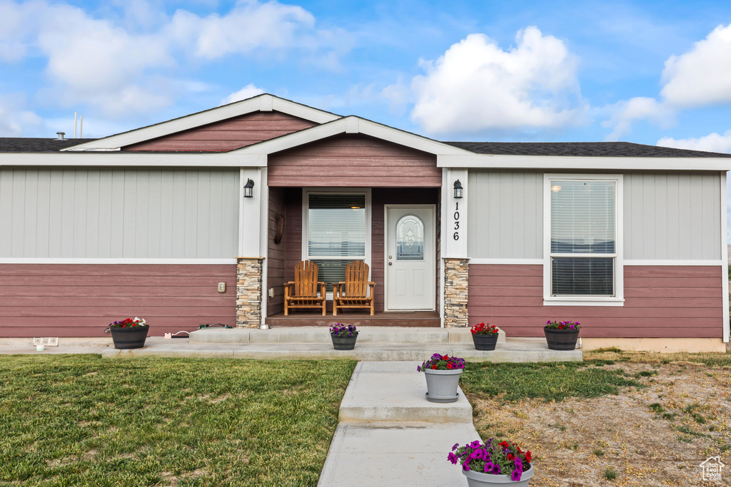 View of front of home with a porch, a front lawn, and stone siding