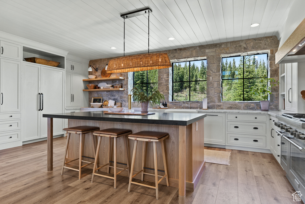 Kitchen featuring open shelves, wooden ceiling, a kitchen island, white cabinetry, and a breakfast bar area