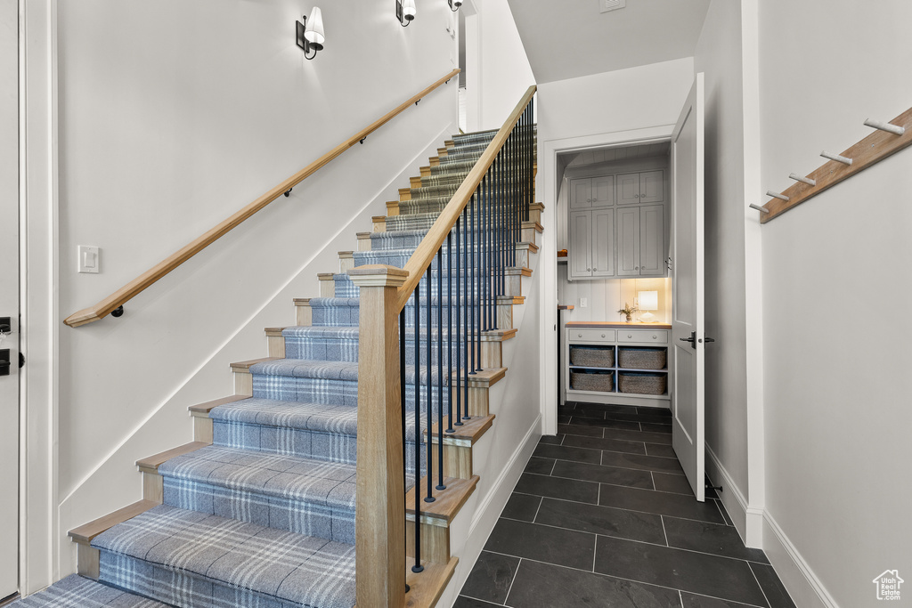 Stairs with tile patterned flooring and baseboards