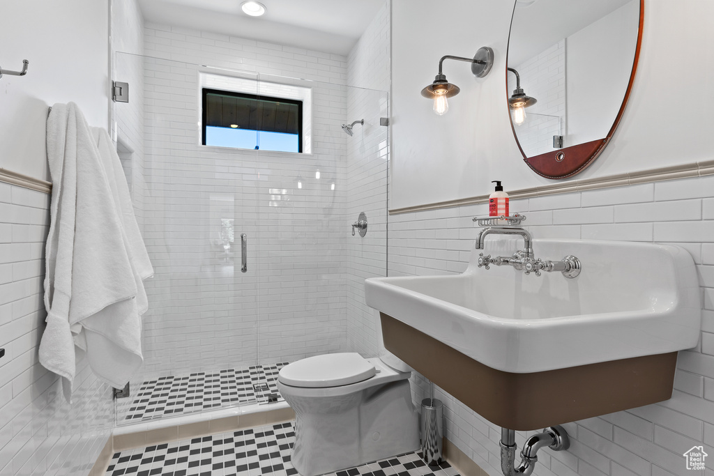Full bath featuring a stall shower, tile walls, and a wainscoted wall
