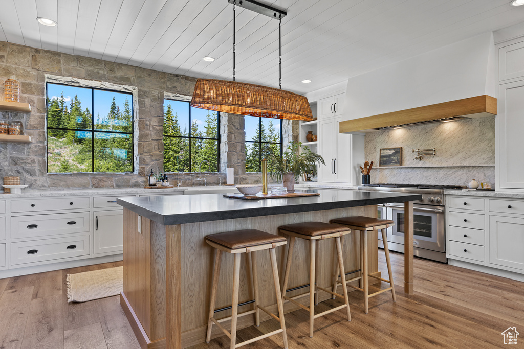 Kitchen featuring double oven range, open shelves, white cabinetry, a kitchen island, and wood ceiling