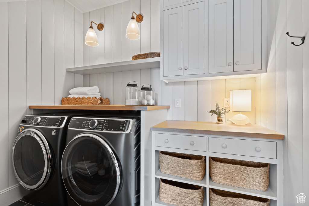 Laundry room with independent washer and dryer, cabinet space, and a decorative wall
