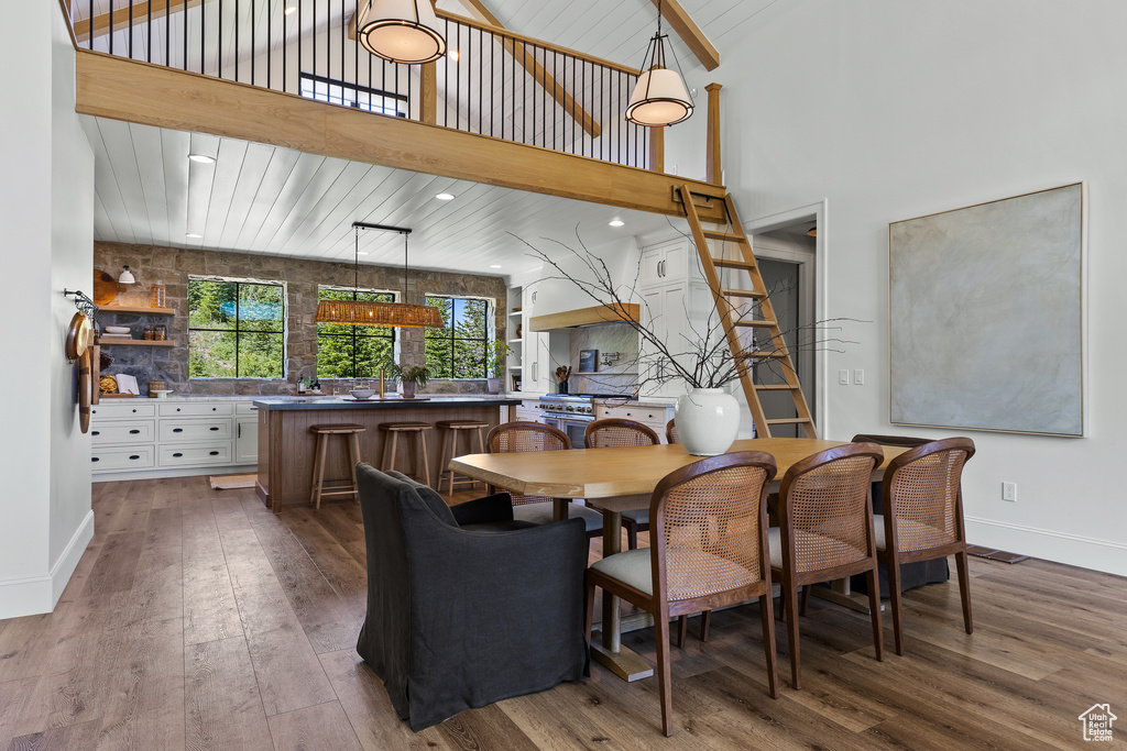 Dining room with wood-type flooring, a high ceiling, and recessed lighting