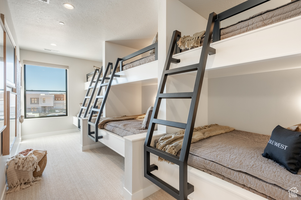 Bedroom with carpet, a textured ceiling, and recessed lighting