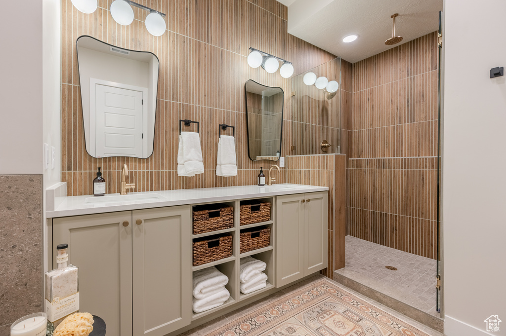 Full bath featuring double vanity, walk in shower, tile walls, and tile patterned flooring