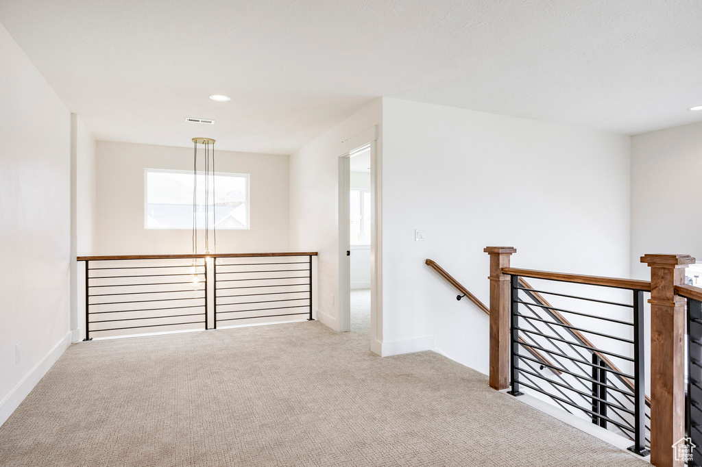 Hallway with an upstairs landing, carpet flooring, and recessed lighting