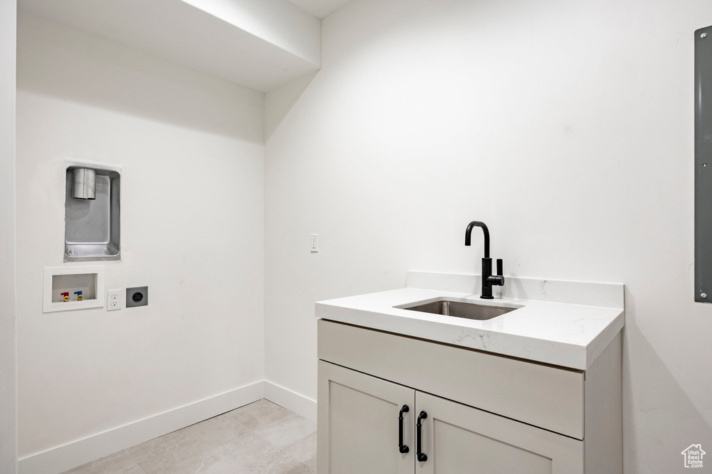 Laundry area with hookup for an electric dryer, washer hookup, cabinet space, and light tile patterned floors