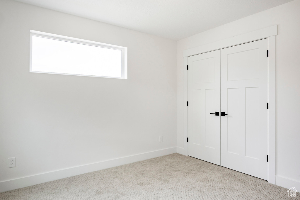 Unfurnished bedroom featuring light colored carpet and a closet