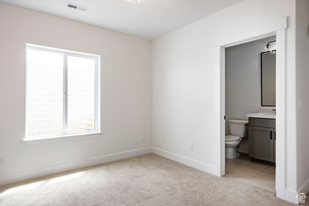 Unfurnished bedroom featuring light carpet and ensuite bath