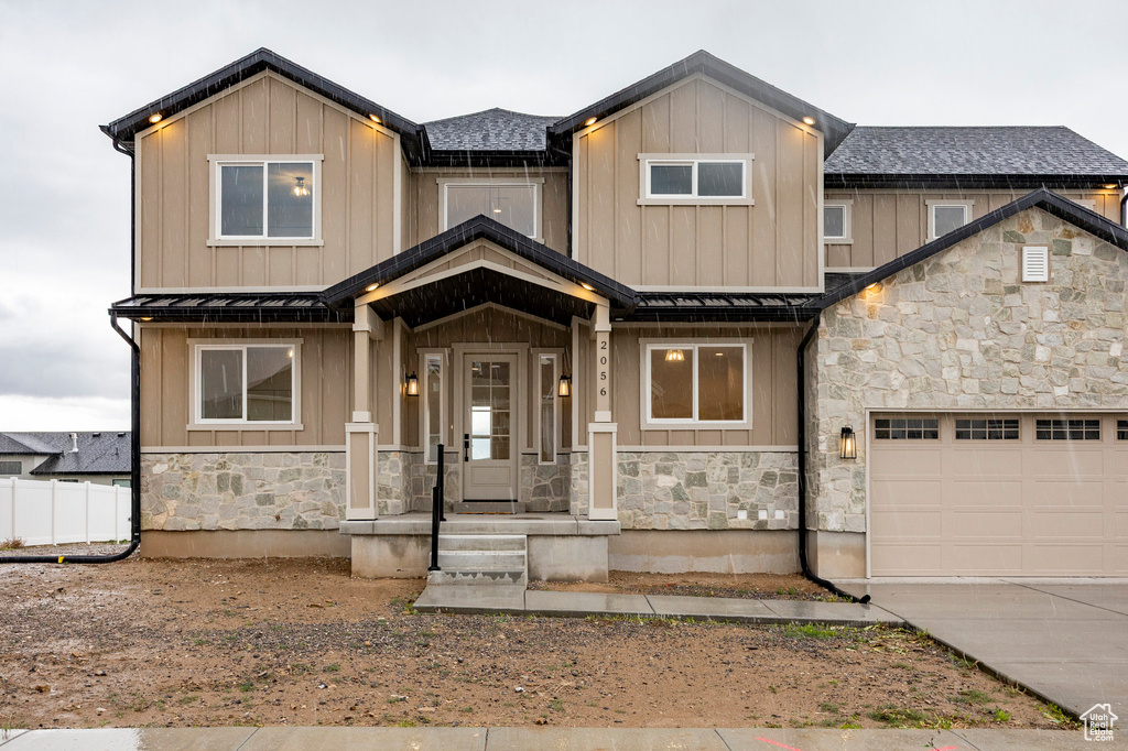 View of front of home with stone siding, a standing seam roof, board and batten siding, a garage, and a metal roof